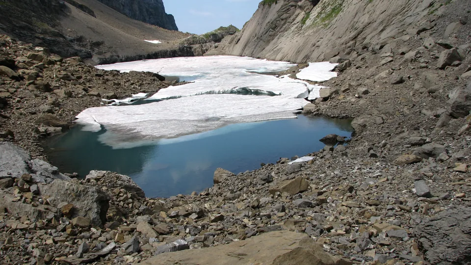 Le lac des Chambres encore partiellement couvert de neige, dans son cirque rocheux